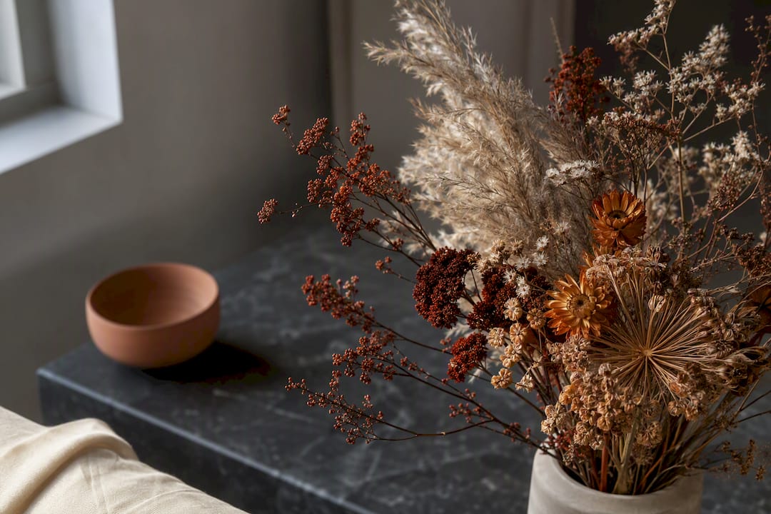Torkade höstblommor med avskurna stjälkar i varm inredning